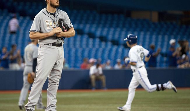 Tampa Bay Rays starting pitcher Erik Bedard looks on as Toronto Blue Jays Steve Tolleson, right, rounds the bases after hitting a solo home run during fourth inning of a baseball game in Toronto on Monday, May 26, 2014. (AP Photo/The Canadian Press, Nathan Denette)