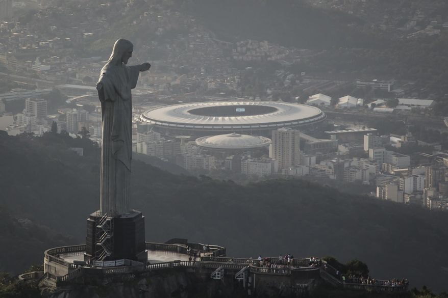 In this May 13, 2014, photo,This aerial view shot through an airplane window shows the Maracana stadium behind the Christ the Redeemer statue in Rio de Janeiro, Brazil. As opening day for the World Cup approaches, people continue to stage protests, some about the billions of dollars spent on the World Cup at a time of social hardship, but soccer is still a unifying force. The international soccer tournament will be the first in the South American nation since 1950. (AP Photo/Felipe Dana, File)
