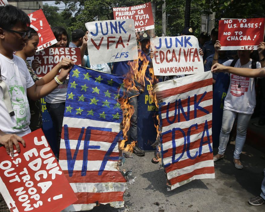 Protesters burn a mock US flag during a rally near the U.S. Embassy in Manila, Philippines Tuesday, May 27, 2014 to protest the recent agreement between the Philippine and U.S. militaries known as the Enhanced Defense Cooperation Agreement (EDCA). Civil society groups, including two former senators, who voted to reject the presence of U.S. military bases and its troops in 1991, has filed a petition at the Supreme Court on Monday questioning the legality of the new security agreement, which was signed during the state visit by US President Barack Obama in late April. (AP Photo/Bullit Marquez)