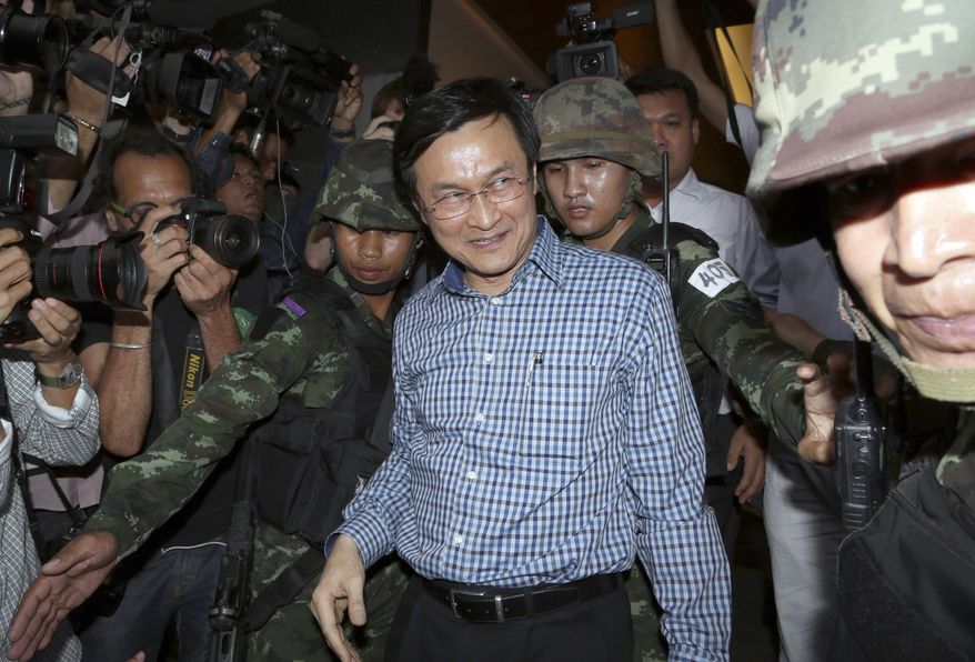 Former Thai Education Minister Chaturon Chaisang, center, walks after being detained by soldiers after a news conference at the Foreign Correspondents' Club of Thailand in Bangkok, Thailand Tuesday, May 27, 2014. Thai troops detained the Cabinet minister who defiantly emerged from hiding on Tuesday to condemn last week's military coup and urge a return to civilian rule, in the first public appearance by any member of the ousted government. (AP Photo/Apichart Weerawong)