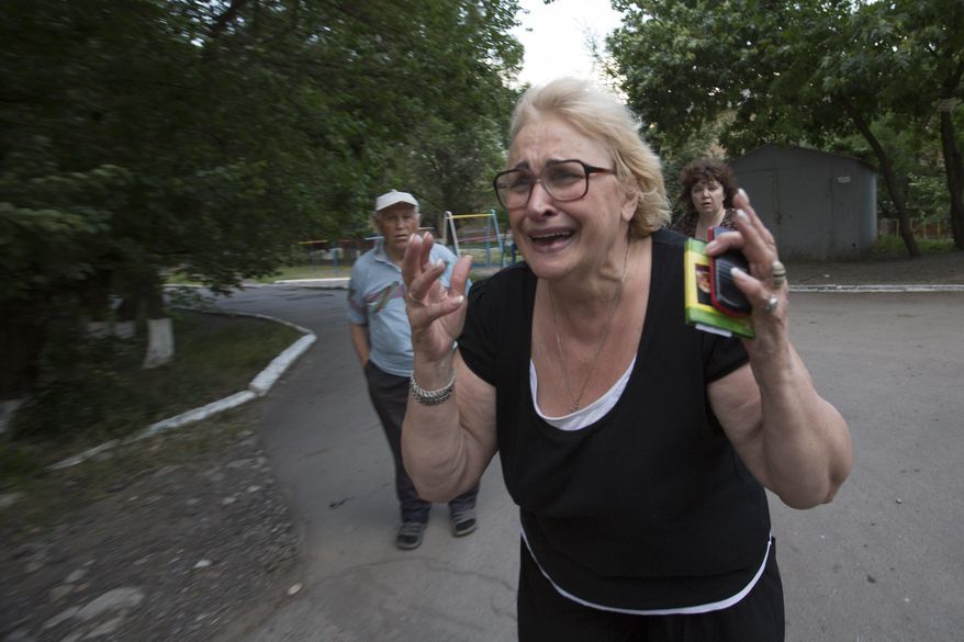 A woman reacts after seeing the lifeless body of a man killed by shrapnel following a shelling from Ukrainian government forces in Slovyansk, Ukraine, Monday, May 26, 2014. Exit polls from Sunday's first round of the new presidential election predict Petro Poroshenko will be elected president in this bitterly divided country, and he vowed "to bring peace to the Ukrainian land", yet he described the separatists as "Somali pirates" and authorities in Kiev launched strikes against the militants. (AP Photo/Alexander Zemlianichenko)