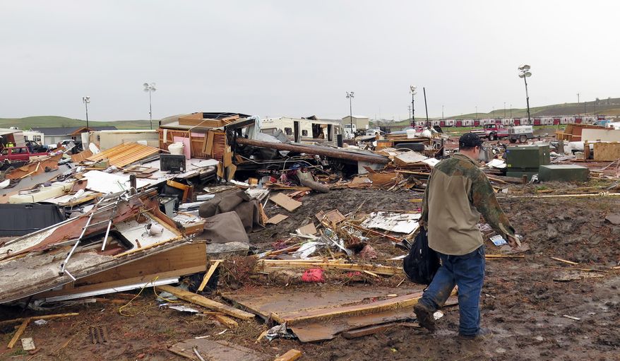 A man walks past trailers Tuesday, May 27, 2014 in Watford City, N.D, that were destroyed by a tornado the night before. Authorities say several were injured and more than a dozen trailers were damaged or destroyed Monday evening when the twister tore through the camp where oil field workers stay. (AP Photo/Josh Wood)