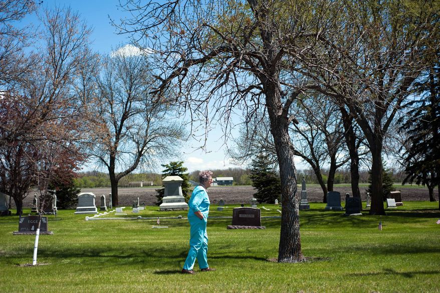 In this May 20, 2014 photo, Lillian Johnson walks back to the car after visiting the graves of her husband, two sons and nephews who are buried at the Lower Wild Rice and Red River Cemetery near Wild Rice, N.D. Johnson has buried her husband and other family members in the tiny cemetery in southeastern North Dakota that would be threatened by a flood protection project meant to save the state’s largest city. (AP Photo/Jesse Trelstad)