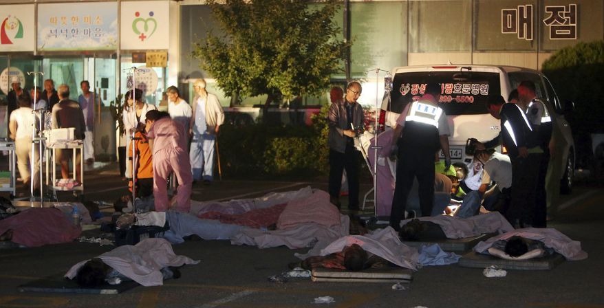 Rescued patients are placed on the ground outside of a hospital in Jangseong, South Korea, Wednesday, May 28, 2014. A fire at the hospital annex housing elderly patients, killed 21 people early Wednesday, officials said. (AP Photo/Yonhap, Hyung Min-woo) KOREA OUT