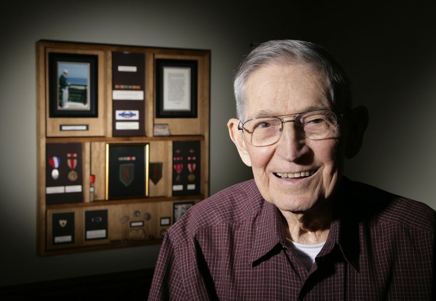 ADVANCE FOR USE MONDAY, JUNE 2, 2014, AND THEREAFTER - In an April 18, 2014 photo, Richard Crum poses for a photo near some of his military memorabilia at his home in Williamston, Mich. Crum landed on Omaha Beach on D-Day, June 6, 1944. (AP Photo/Al Goldis)