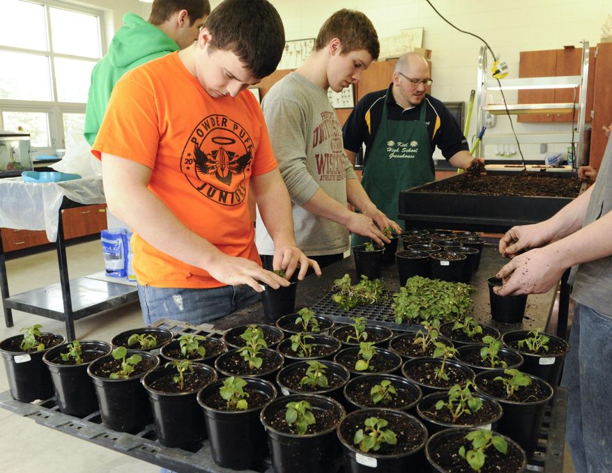 In this photo taken on May 20, 2014, from left, junior Trevor Agnew, senior Aaron Field, agricultural teacher David Friend and senior Jordan Bonde (hidden) plant impatiens starter plants during Plant Science class inside the new head house that is connected to a greenhouse, which is part of the new Agriculture Research Facility at Kiel High School in Kiel, Wis. (AP Photo/Herald-Times Reporter, Sue Pischke) NO SALES