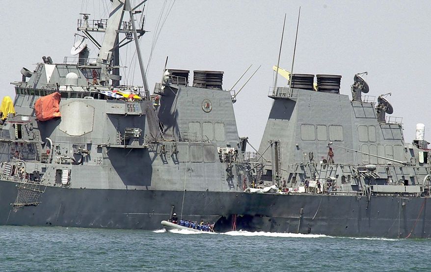 FILE -- In this Sunday Oct. 15, 2000 file photo, investigators in a speed boat examine the hull of the USS Cole at the Yemeni port of Aden, after a powerful explosion ripped a hole in the U.S Navy destroyer, killing at least 17 sailors and injuring some 30 others. Prosecutors are asking a military judge in Guantanamo Bay to reconsider his order that they share with defense attorneys details about a detainee’s experience in secret CIA prisons after he was arrested in connection with the deadly attack on the USS Cole in Yemen. (AP Photo/Dimitri Messinis, File)
