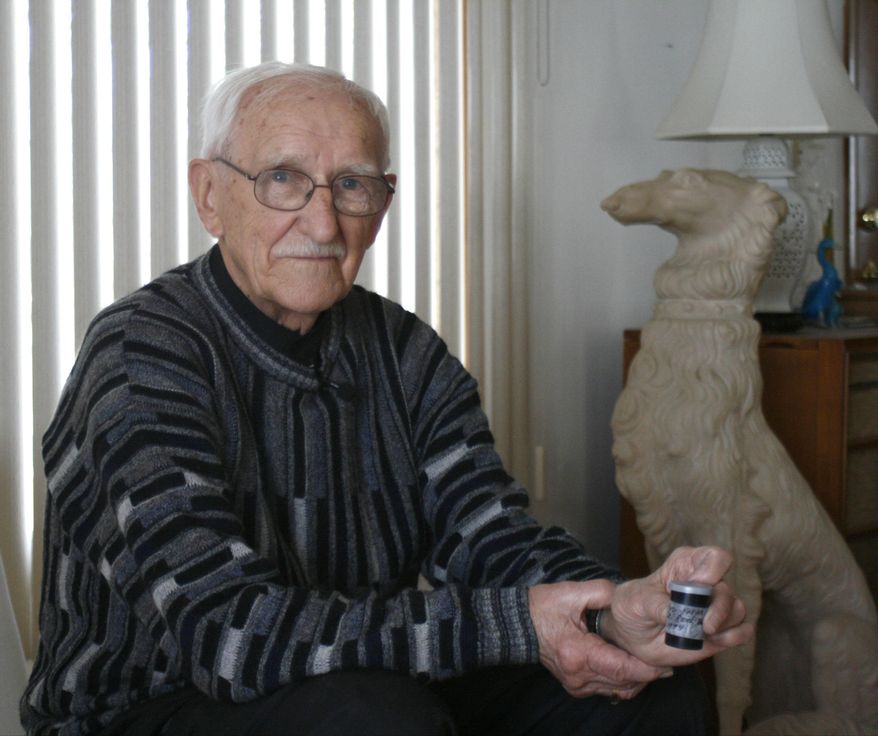 ADVANCE FOR USE MONDAY, JUNE 2, 2014, AND THEREAFTER - This March 24, 2014, taken in Racine, Wis., James Krucas poses for a photo as he holds a container of sand collected in 1994 from the beach Normandy, France, where he landed on June 6, 1944, during the D-Day invastion. Krucas is one of the few remaining veterans of the D-Day invasion in Europe. (AP Photo/M.L. Johnson)