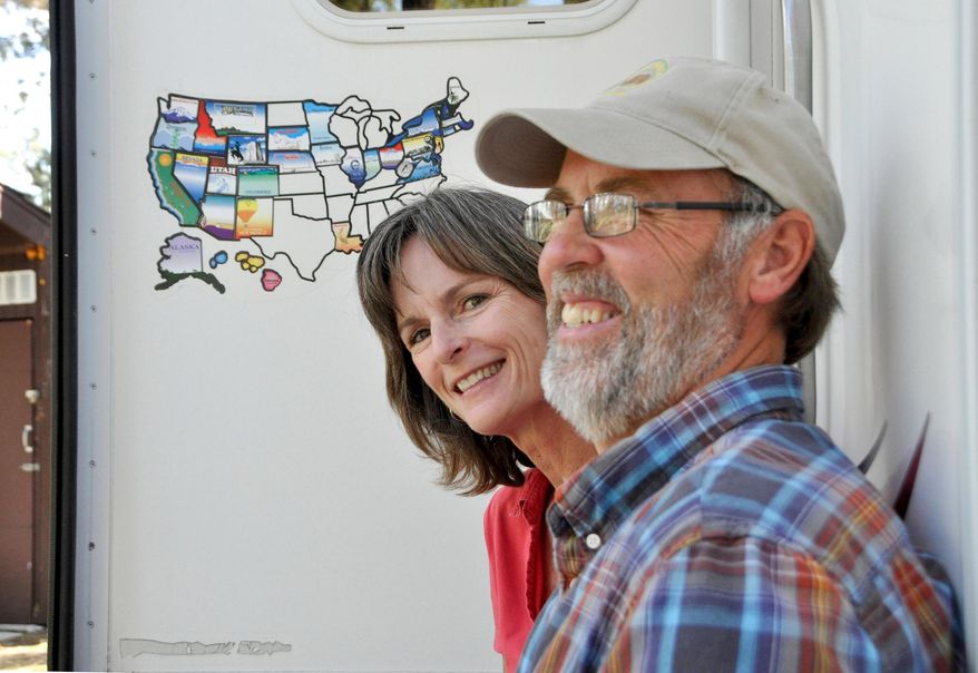 In this May 20, 2014 photo, Susan and Larry Dach, 2014 summer campground hosts at Dragoon Campground north of Spokane, Wash., stand by their RV in Spokane. The Dachs have traveled and camped in their RV throughout the western and northern United States, and as far north as Alaska, since retiring in 2008. The couple, who cut costs by earning free camping as hosts, say they're planning their future trips to cover the South. (AP Photo/The Spokesman-Review, Rich Landers) COEUR D'ALENE PRESS OUT