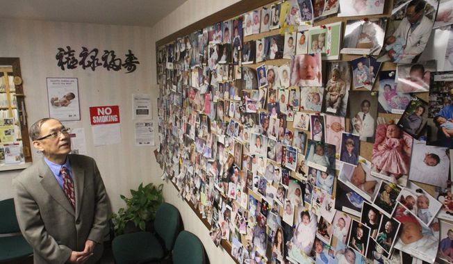 Dr. Jung Wu M.D. has delivered thousands of babies in Livingston County as shown by a collection of photos attached to his Howell office wall. (AP Photo/Livingston County Daily Press &amp;amp; Argus, Alan Ward)