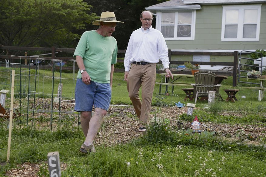 In this photo from May 29, 2014, State Sen. Burke Harr, right, and urgan gardner Paul Goetzinger, left, walk the paths of the Benson community garden in Omaha, Neb. Sen. Harr wants to expand the use of community gardens in urban areas. He is launching a study this summer to try to make it easier to start community gardens, possibly by allowing them to grow on public land. (AP Photo/Nati Harnik)