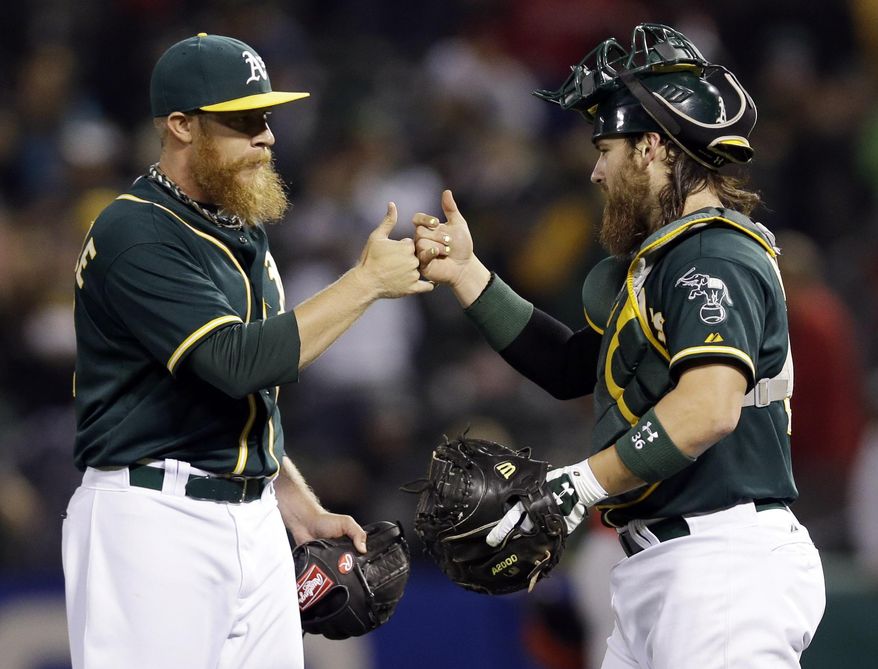 Oakland Athletics reliever Sean Doolittle, left, high-fives catcher Derek Norris at the end of a 9-5 win over the Los Angeles Angels during a baseball game on Friday, May 30, 2014, in Oakland, Calif. (AP Photo/Marcio Jose Sanchez)