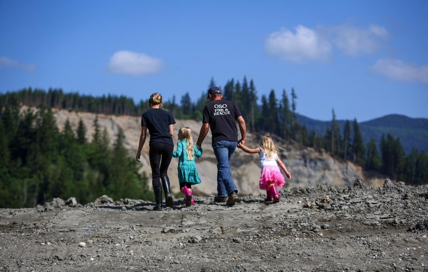 Oso, Wash. firefighter Tim Harper leads his wife Jaimie and daughters Cameron, 7, left, and Lyla, 4, to a ridge to look at the Oso debris field on Saturday, May 31, 2014. A little more than two months after the Oso mudslide destroyed a neighborhood and killed 43 people, the highway through the heart of the slide reopened to vehicle traffic. (AP Photo/seattlepi.com, Joshua Trujillo)