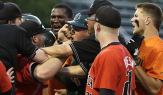 Miami assistant coach Gino DiMare, fourth from right, argues with a Texas Tech coach, second from left, as they are restrained by umpires after David Thompson, right, was out at first in the third inning during an NCAA college baseball regional tournament in Coral Gables, Fla., Sunday, June 1, 2014. (AP Photo/Lynne Sladky)