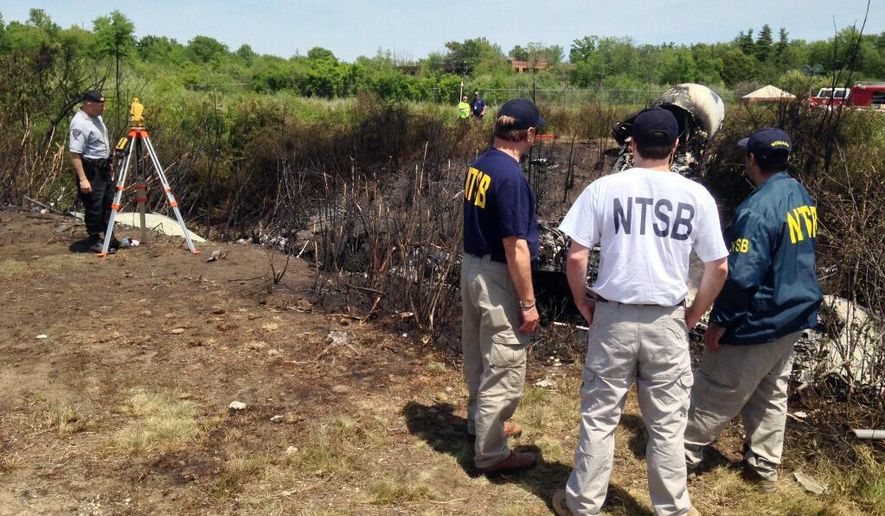 In this Sunday, June 1, 2014 photo provided by the National Transportation Safety Board, shows NTSB investigators at the scene of a plane that plunged down an embankment and erupted in flames during a takeoff attempt Saturday night at Hanscom Field in Bedford, Mass. The co-owner of the Philadelphia Inquirer newspaper, Lewis Katz, was killed along with six other people in the crash just days after reaching a deal that many hoped would end months of infighting at the newspaper and help restore it to its former glory. (AP Photo/National Transportation Safety Board)