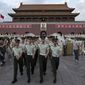 ** FILE ** In this May 28, 2014, photo, paramilitary policemen march out of Tiananmen Gate to clear tourists from the area for a flag-lowering ceremony on Tiananmen Square in Beijing. (AP Photo/Alexander F. Yuan)