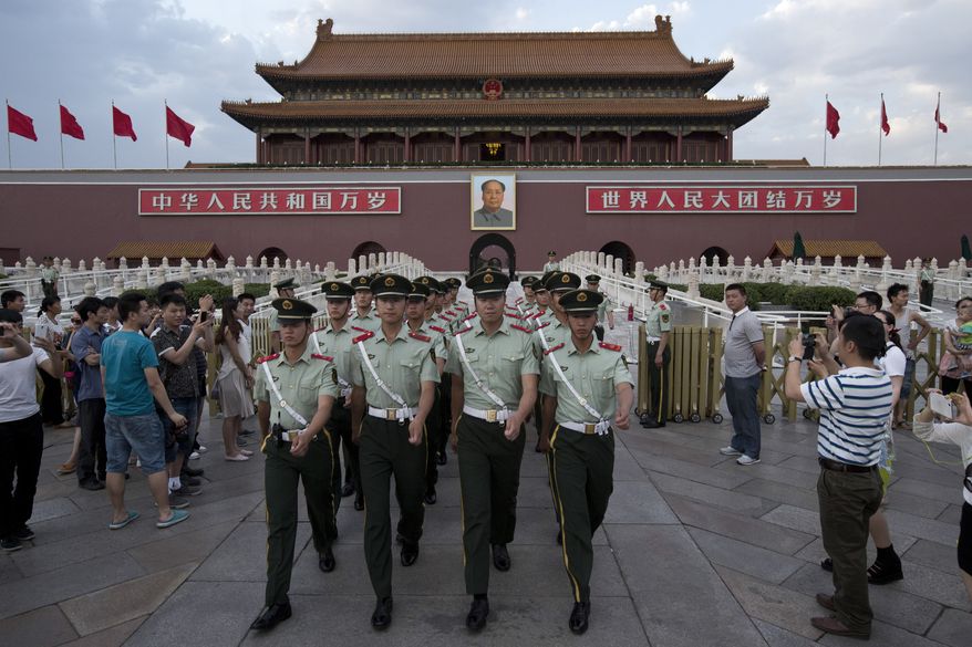 ** FILE ** In this May 28, 2014, photo, paramilitary policemen march out of Tiananmen Gate to clear tourists from the area for a flag-lowering ceremony on Tiananmen Square in Beijing. (AP Photo/Alexander F. Yuan)