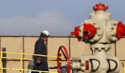 ** FILE ** This March 25, 2014, file photo shows heat from machinery distorts the air as a worker watches over a hydraulic fracturing operation at an Encana Corp. gas well near Mead, Colo. (AP Photo/Brennan Linsley, File)