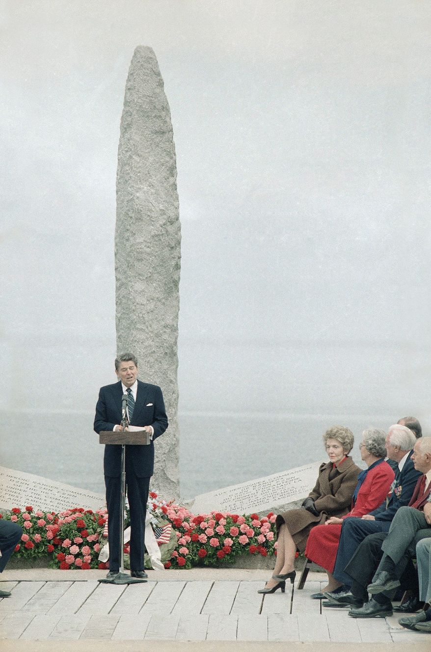 Photo shows general view of the ceremony at Pointe Du Hoc, France, on Wednesday, June 6, 1984 as President Ronald Reagan delivers his speech shortly after his arrival in Normandy.   Sitting are right is Mrs. Nancy Reagan with veterans of the 2nd Ranger Battalion that conquered the cliffs. Left, the memorial monument remembering the invasion 40 years ago. (AP Photo/Ron Edmonds)