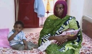 In this image made from an undated video provided Thursday, June 5, 2014, by Al Fajer, a Sudanese nongovernmental organization, Meriam Ibrahim, sitting next to Martin, her 18-month-old son, holds her newborn baby girl that she gave birth to in jail last week, as the NGO visits her in a room at a prison in Khartoum, Sudan. The Sudanese woman sentenced to death for refusing to recant her Christian faith after allegedly converting from Islam has appealed the sentence, her lawyer said. (AP Photo/Al Fajer)