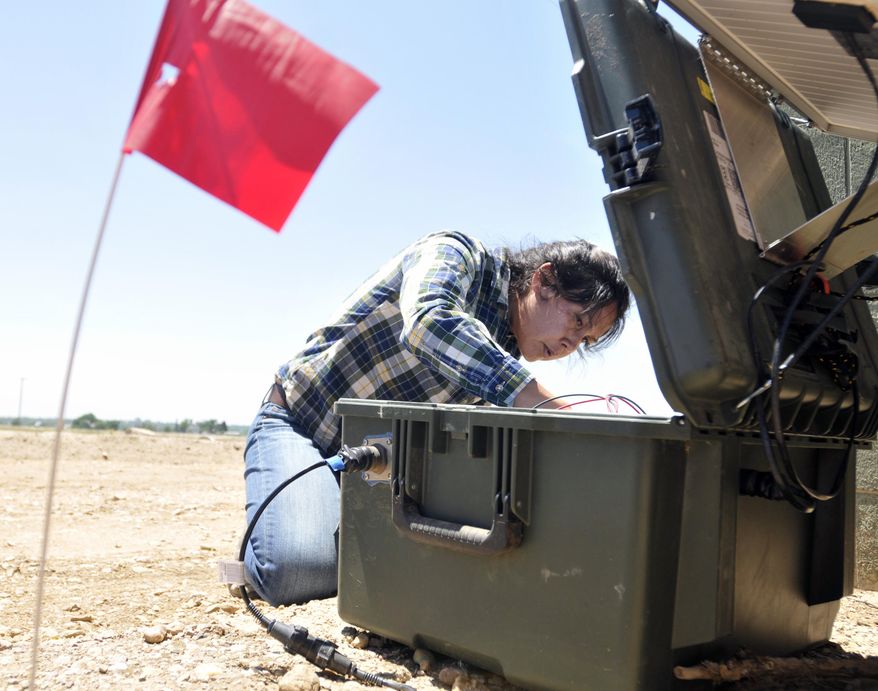 In this June 5, 2014 photo, a red flag marks the seismic monitor buried in the ground as Jenny Nakai, a graduate student in seismology from University of Colorado at Boulder, begins checking one of the instruments above near the intersection of Weld County Road 64 south of Lucerne, Colo. Anne Sheehan, a geophysicist from the University of Colorado is hoping to settle the question of whether a small earthquake last weekend near Greeley was caused by wastewater injection wells. (AP Photo/The Greeley Tribune, Joshua Polson)