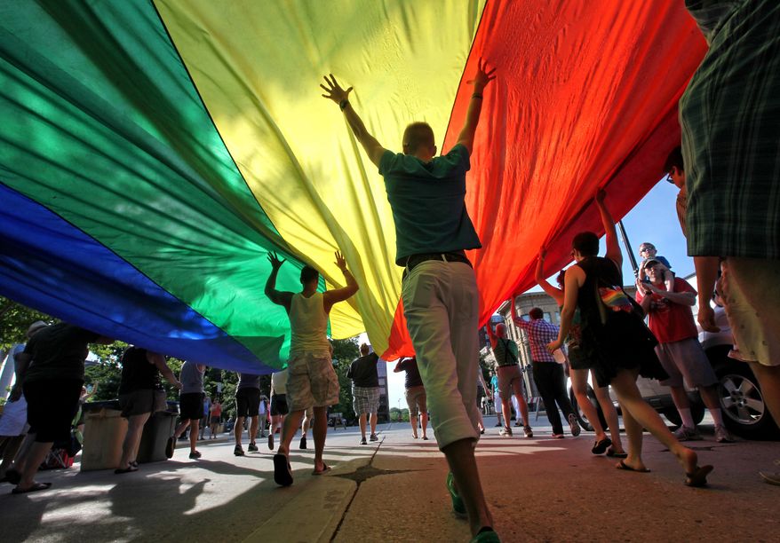 FILE - In this June 26, 2013, file photo, supporters of a U.S. Supreme Court ruling which overturned the federal Defense of Marriage Act carry a large rainbow flag during a parade around the Wisconsin State Capitol in Madison, Wis. A federal judge has struck down Wisconsin's ban on same-sex marriage Friday, June 6, 2014, ruling it unconstitutional. It wasn't clear whether same-sex marriages could immediately begin. (AP Photo/Wisconsin State Journal, John Hart)