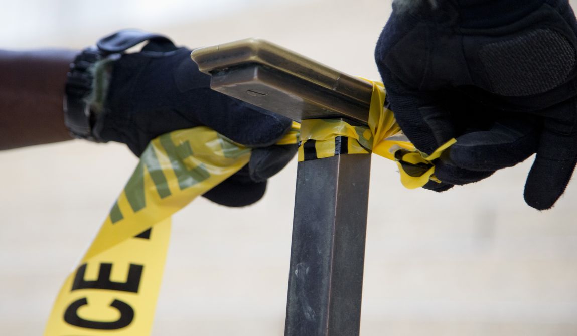A police officer ties police tape to a handrail. (Associated Press) ** FILE **