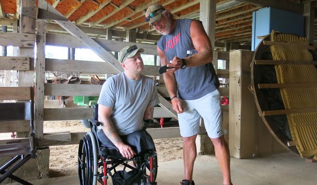 Retired NFL quarterback Brett Favre, right, and U.S. Army veteran Rusty Dunagan trade hunting stories and photos inside a barn at the Lauderdale County, Miss., farm of actress Sela Ward on Monday, June 9, 2014.  (AP Photo/The Meridian Star, Terri Ferguson Smith )  