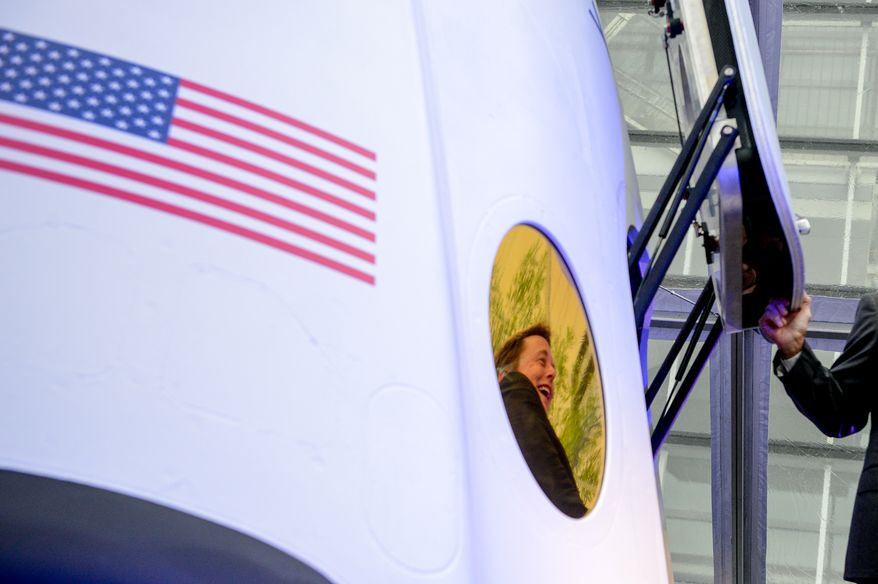 SpaceX CEO and Chief Designer Elon Musk, seen in reflection on the spacecraft window, introduces the companies next generation Dragon spacecraft at an event held at the Newseum, Washington, D.C., Tuesday, June 10, 2014. (Andrew Harnik/The Washington Times)