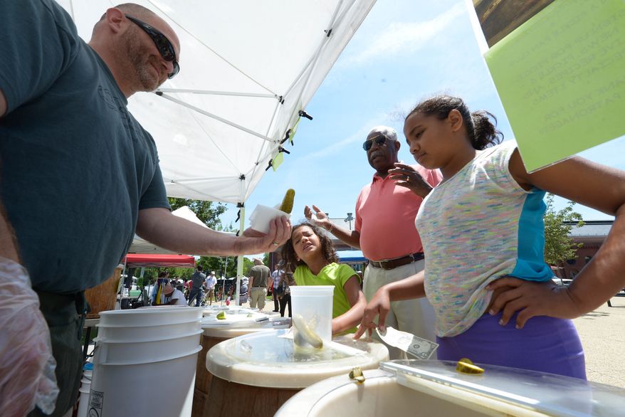 A Sour Taste! Jason Gallant, left, offers Marisa Covington, 6, far left, Carl Cole and Ashley Covington, 10 and a sample of pickles at Eastern Market on Sunday, June 15. The girls were spending Father’s Day with their great-grandfather. Khalid Naji-Allah/ Special to The Washington Times