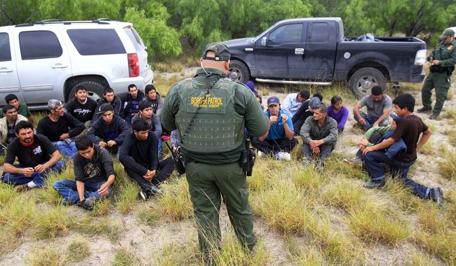 ** FILE ** In this Thursday, April 17, 2014, photo, immigrants suspected of being in the country illegally sit in a group after U.S. Border Patrol agents detained at least 80  immigrants who&#x27;d been living in a makeshift encampment in suburban McAllen, Texas. (AP Photo/The Monitor, Gabe Hernandez)