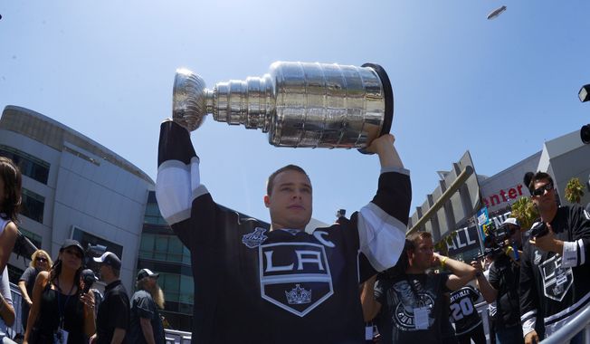 Los Angeles Kings right wing Dustin Brown holds up the NHL hockey Stanley Cup trophy while riding in a parade, Monday, June 16, 2014, in Los Angeles. The parade and rally were held to celebrate the Kings&#x27; second Stanley Cup championship in three seasons. The Kings defeated the New York Rangers for the title. (AP Photo/Mark J. Terrill) 