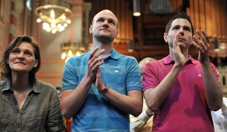 In this June 14, 2014 photo, Brigitte Schaefer, left, her son Tim Schaefer, center, and Tim's partner, John Duncan, applaud as Frank Schaefer receives an Open Door Award for his public advocacy in Massachusetts, at Old South Church, in Boston. Frank Schaefer, a Methodist pastor who was defrocked for officiating his son Tim's wedding to another man, accepted the award the weekend before a Methodist judicial panel was scheduled to hear his appeal to continue in the ministry. (AP Photo/Josh Reynolds)