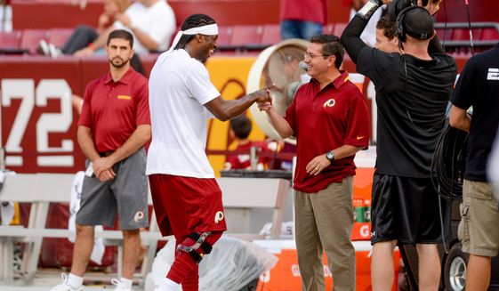 Washington Redskins quarterback Robert Griffin III (10), center left, greets Washington Redskins owner Dan Snyder, center right, during warm ups before the Washington Redskins play the Pittsburgh Steelers in NFL preseason football at FedEx Field, Landover, Md., Monday, August 19, 2013. (Andrew Harnik/The Washington Times) **FILE**