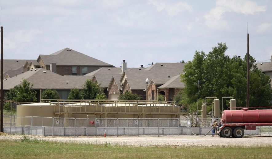 Natural gas well holding tanks sit next to a subdivision of homes in Denton, Texas, Thursday, May 29, 2014. This North Texas city wants less gas and more hot sauce. Unlike most Texas communities that have embraced the lucrative oil and natural gas booms, Denton leaders are considering a petition to ban hydraulic fracturing and are trying to persuade Sriracha to move its massive pepper-grinding operations from California. Although sitting on top of the Barnett Shale, believed to hold one of the largest natural gas reserves in the U.S., Denton would rather be known for having the largest community garden in the U.S. (AP Photo/LM Otero)