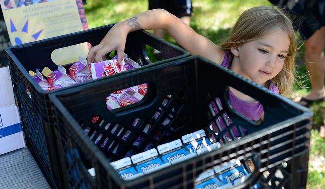 Gabby Frasch, 5, grabs a carton of milk for lunch, which was being served through the Summer Food Service Program delivered by the Green Bay Area Public School District to the Brown County Library&#x27;s Southwest branch in Green Bay, Wis. on Monday, June 16, 2014. (AP Photo/The Green Bay Press-Gazette, Kyle Bursaw) NO SALES