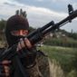 A pro-Russian fighter holds a gun during a handover of the bodies of Ukrainian troops killed in a plane shot down near Luhansk, at a check point in the village of Karlivka near Donetsk, eastern Ukraine, Wednesday, June 18, 2014. The two sides managed to arrange a brief truce Wednesday evening in the eastern town of Karlivka to allow pro-Russian forces to hand over the bodies of 49 Ukrainian troops who died when the separatists shot down a transport plane bound for the airport in Luhansk last weekend.  (AP Photo/Evgeniy Maloletka)