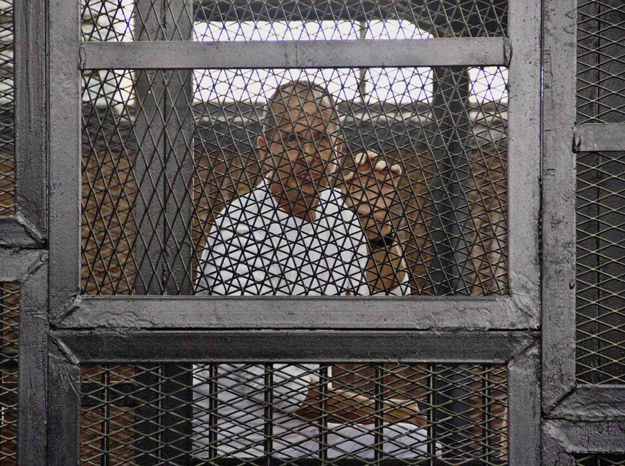 FILE - In this May 3, 2014 file photo, Al-Jazeera's award-winning Australian correspondent Peter Greste appears in a defendants' cage in the Police Academy courthouse along with several other defendants during a trial on terror charges in Cairo, Egypt. Australian Prime Minister Tony Abbott said Monday, June 23 that he told Egyptian President Abdel Fatah al-Sisi that the jailed Australian journalist is innocent of charges that he supported the outlawed Muslim Brotherhood. (AP Photo/Hamada Elrasam, File)