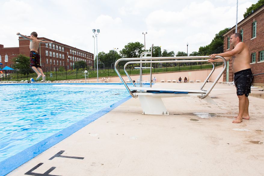Ty Sidzyik, age 12, jumps off of the diving board at Banneker Pool Monday as his father, Chris, watches. The family, from Omaha, Nebraska, is in town visiting the city. Keith Lane/Special to the Washington Times