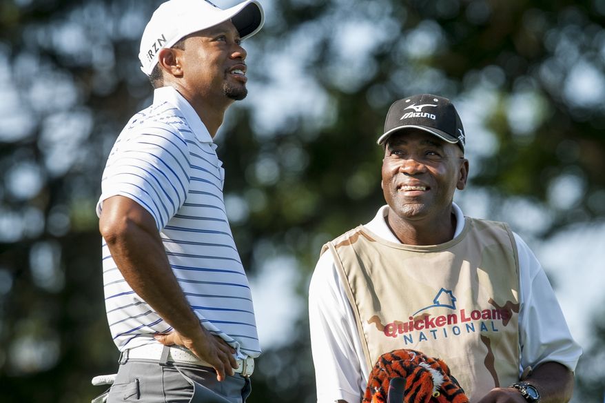 Marine Master Gunnery Sgt. Anthony Russell talks with Tiger Woods on the 17th hole during the pro-am at the Quicken Loans National golf tournament being played on Wednesday at Congressional Country Club in Bethesda, Maryland. A new part of the pro-am event, enlisted military personnel from Maryland, Virginia and D.C. served as caddies for professional players on the 17th hole, wearing special camouflage caddie bibs. Russell, 47, has been in the Marine Corps for 28 1/2 years and is a veteran of Operations Desert Shield and Desert Storm. He lives in Safford, Va. PHOTO: Pete Marovich Special to The Washington Times