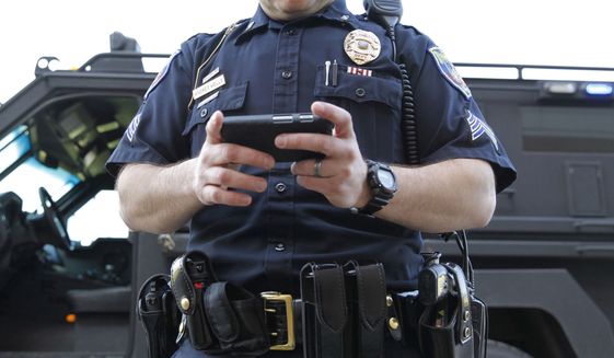WEB STOCK Police Officer inspects a cell phone. (AP Photo)