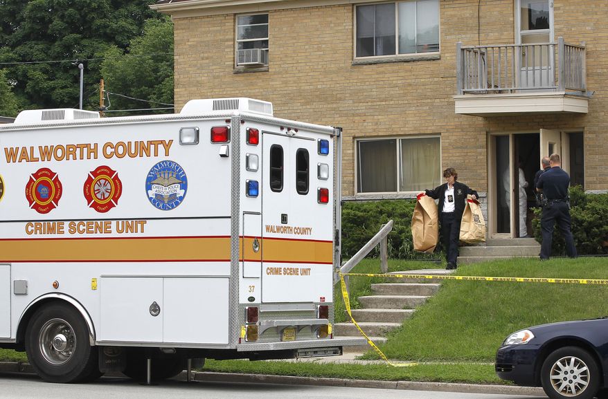 In this photo taken on Wednesday, June 25, 2014, Walworth County investigators carry bags full of material from an apartment in West Allis, Wis., after picking up a suspect allegedly involved in two murders where the bodies were found in suitcases along a rural road in Geneva Township several weeks ago. (AP Photo/Milwaukee Journal-Sentinel, Gary Porter)