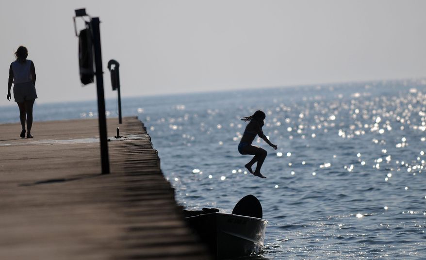 A young swimmer jumps into Lake Michigan off of the pier in Montegue, Mich. White Lake in Muskegon County was declared a Great Lakes "area of concern" in 1985 because of severe environmental degradation, primarily from industrial and municipal wastes. (AP Photo/Detroit News, Elizabeth Conley)