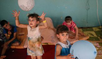 Displaced Iraqi Christian girls who fled with their parents from the Christian village near Mosul province in Iraq, play by their balloons at a temporary shelter for the displaced Christian families in Ankawa, a suburb of Irbil, with a majority Christian population, Iraq. (AP Photo/Hussein Malla)