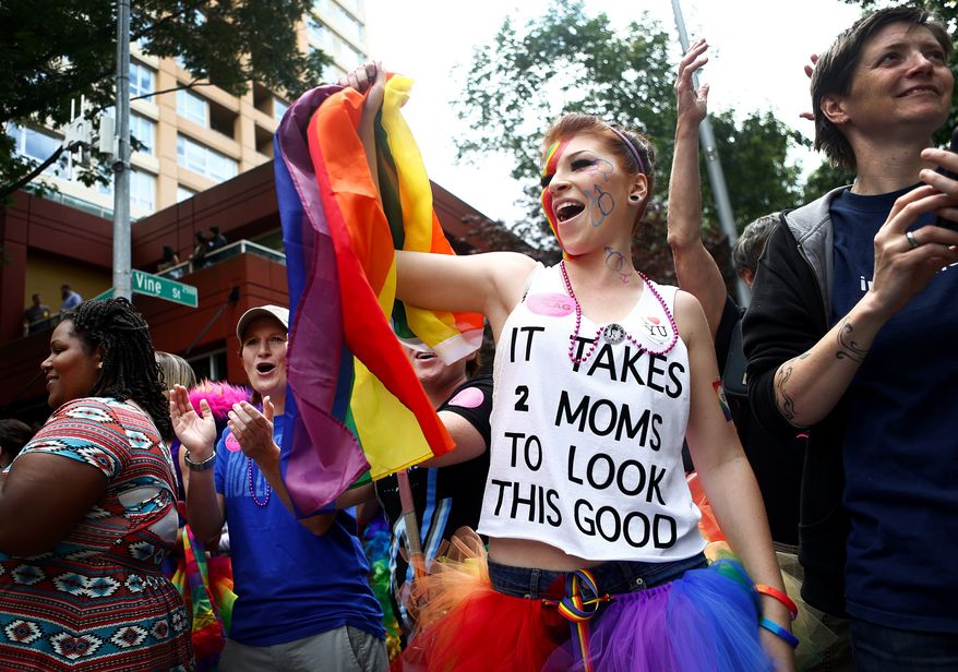 ** FILE ** Laura Taylor, attends the pride parade with her parents Kelle Taylor, in blue, and Stephanie Taylor, center, in black, and waves a rainbow flag as she watches floats go by on 4th Avenue and Vine Street during the 40th annual Seattle Pride Parade on Sunday, June 29, 2014. This year's theme was "Generations of Pride," to honor those who "fought the early battles" and who are "continuing to advocate for equality in changing times." (AP Photo/The Seattle Times, Lindset Wasson)