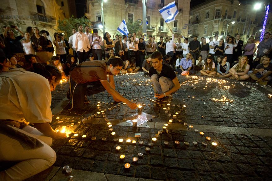 Israelis light candles as they gather in Jerusalem after the announcement that the bodies of the three missing teenagers were found near the West Bank town of Hebron, late Monday, June 30, 2014. The Israeli military found the bodies of three missing teenagers on Monday, just over two weeks after they were abducted in the West Bank, allegedly by Hamas militants. The grisly discovery culminated a feverish search that led to Israel's largest ground operation in the Palestinian territory in nearly a decade and raised fears of renewed fighting with Hamas. Israeli Prime Minister Benjamin Netanyahu was huddling with his Security Cabinet late Monday to discuss a response. (AP Photo/Sebastian Scheiner)
