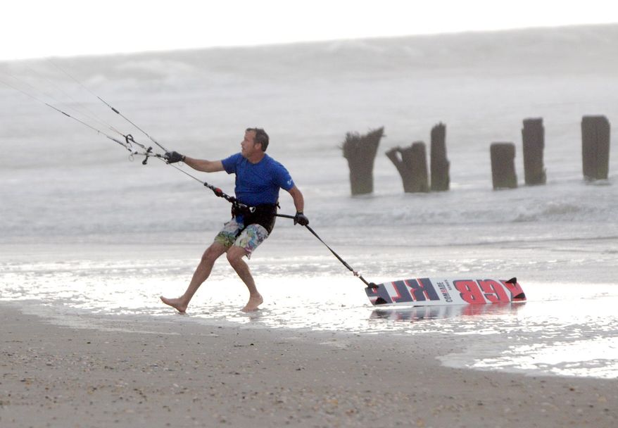 Kite boarder Pete Nero secures his kite as darks clouds and rain move in on the north end of Carolina Beach, N.C., Thursday, July 3, 2014. Residents along the coast of North Carolina are bracing for the arrival of the Hurricane Arthur, which threatens to give the state a glancing blow on Independence Day. (AP Photo/Wilmington Star-News, Mike Spencer)