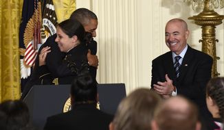 President Barack Obama hugs Army Sgt. Stephanie Van Ausdall after she had trouble in leading the Pledge of Allegiance following a naturalization ceremony for active duty service members and civilians, Friday, July 4, 2014, in the East Room of the White House in Washington. Deputy Homeland Security Secretary Alejandro Mayorkas applauds at right. (AP Photo/Susan Walsh)