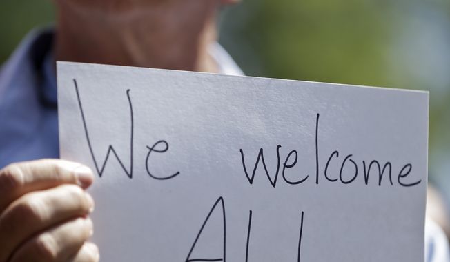 A man holds up a sign during a rally in support of immigrants in San Diego. A Texas bishop said Sunday that the debate over unaccompanied youths at the southern U.S. border has focused on their illegal status and what to do with them but has ignored the root causes of the problem.  (AP Photo/Gregory Bull)