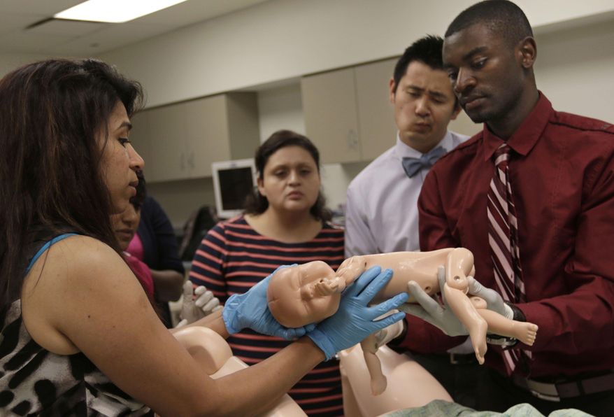 In this June 25, 2014 photo, interns gather around during an intern boot camp exercise taught by both Northwestern Memorial Hospital and Northwestern University's Feinberg School of Medicine in Chicago. (AP Photo/Stacy Thacker)